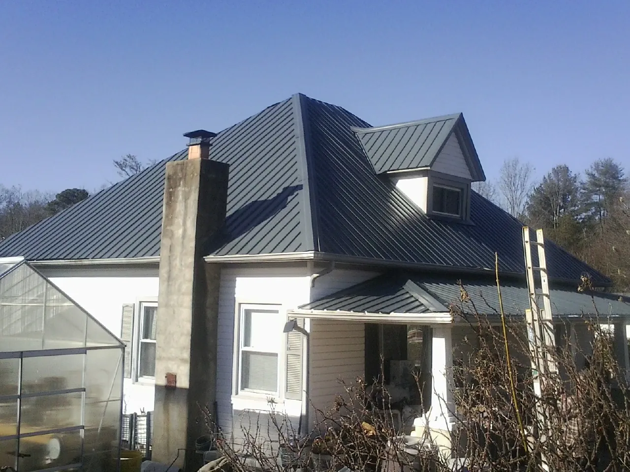 Dark blue standing seam metal roof on a white farmhouse with dormer — Slate & Tile Roof Repair by Roofing Brothers in Chicora