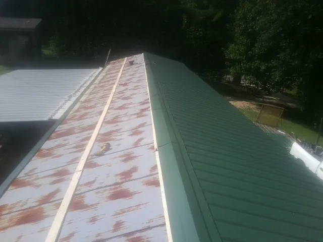 Old rusted panels beside newly installed green metal roofing — Wind Damage Roof Repair by Roofing Brothers in Chicora