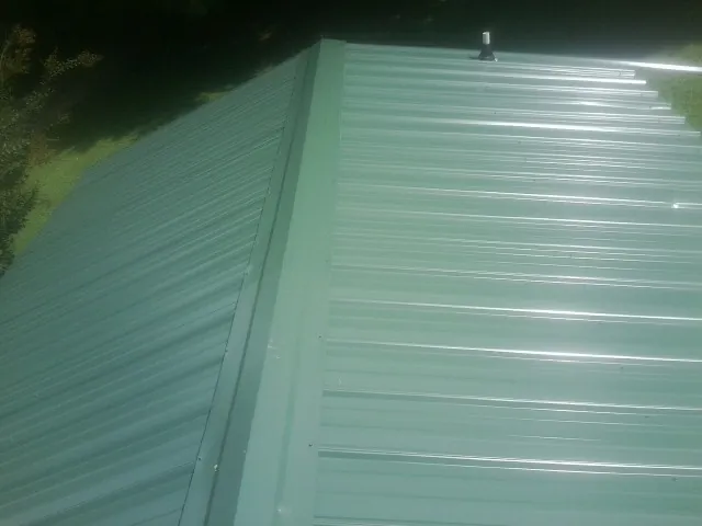 New green metal panels meeting at the ridge of a roof — Flat Roof Repair work by our crew in Chicora