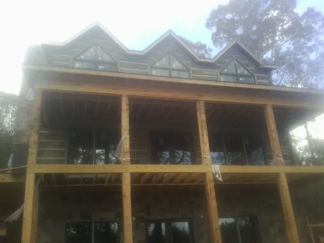 Dormers and porch framing on a large log home under construction — Roof Coating work by our crew in Chicora