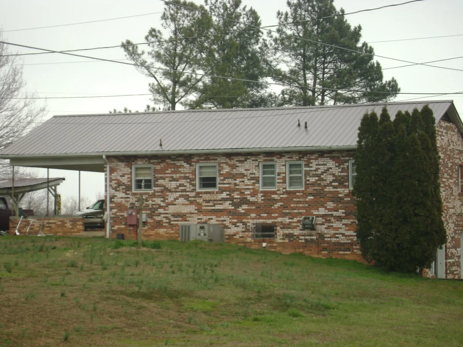 Gray metal roof on a brick split level home with a carport in Chicora