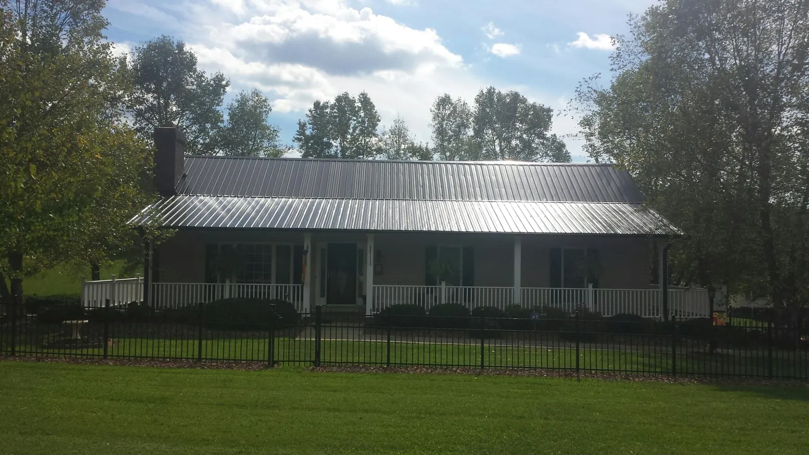 Gray metal roof on a brick ranch with a full width front porch — Gutter Guard Installation work by our crew in Chicora