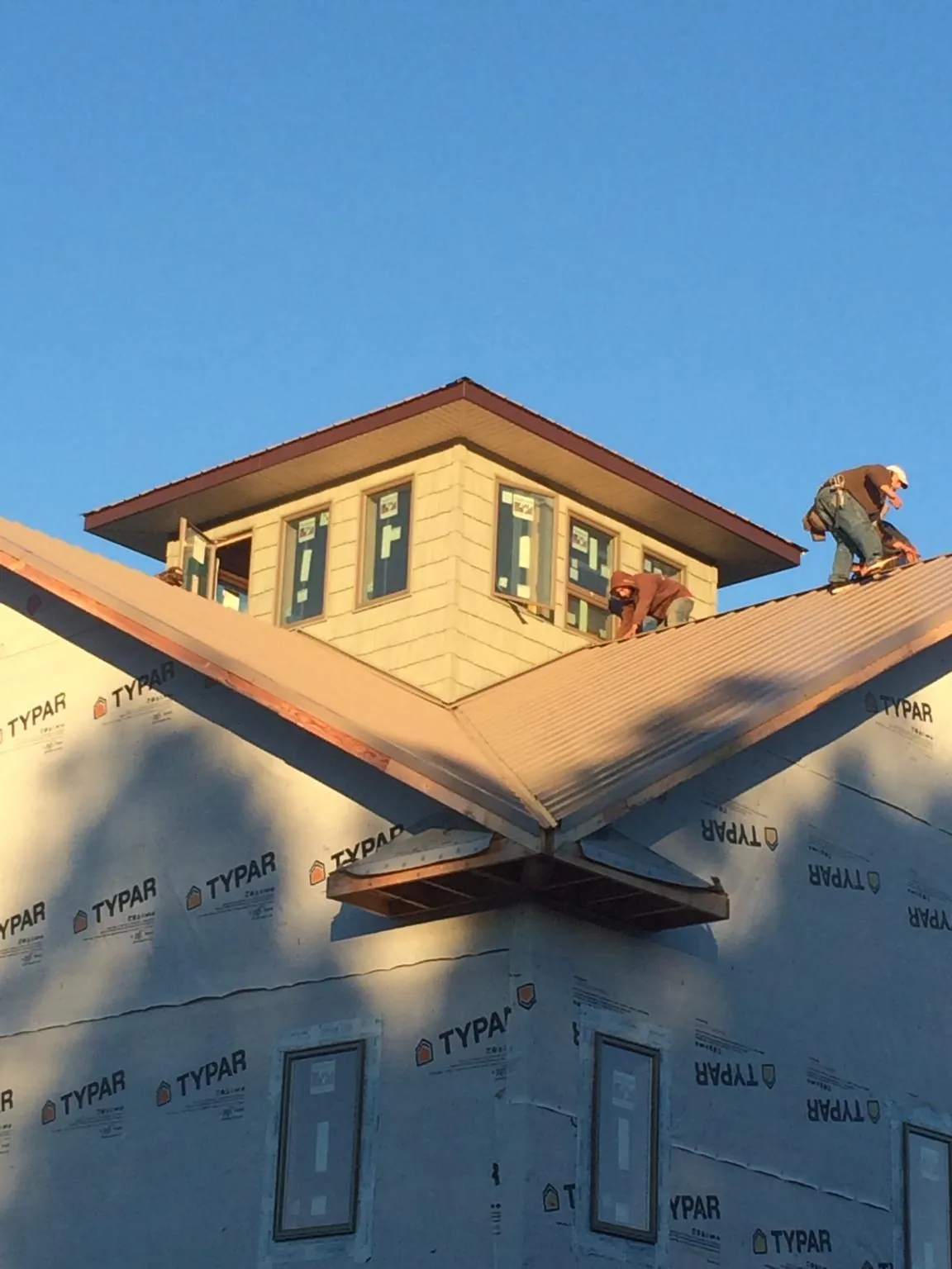 Roofers working around a rooftop cupola on a new metal roof at sunset — Roof Waterproofing in Chicora by Roofing Brothers